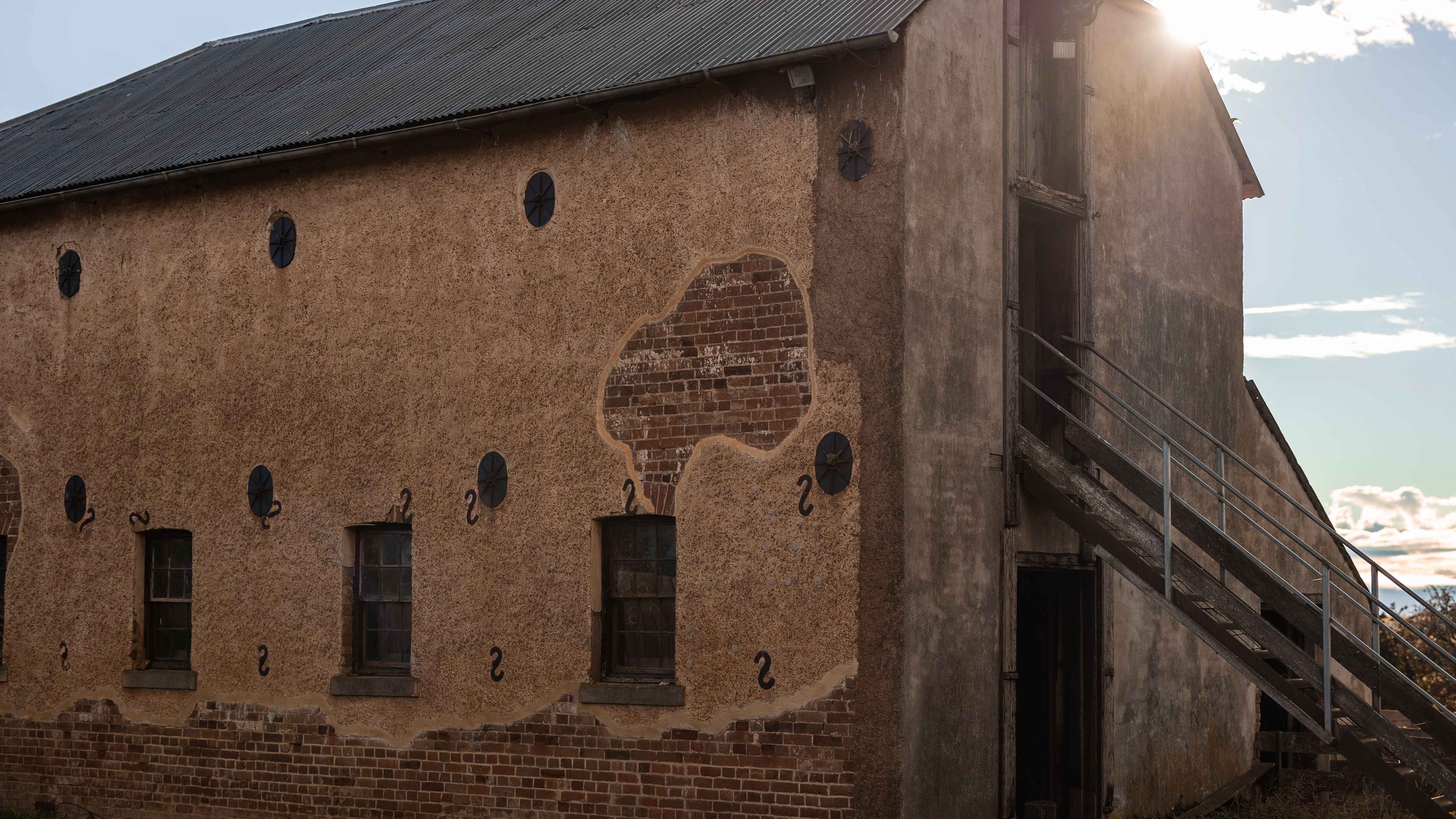 The brick granary built circa 1830 is constructed of brick and is two floors high.  A peddle render covers the bricks but has come off along the base of the building and at one end.  Steel oval plates and S brackets were used to strengthen the walls.  The end of the building has cement render and recently a flight of steel stairs was added leading to the second floor. Photo: Kate von Stieglitz / Tourism Australia.