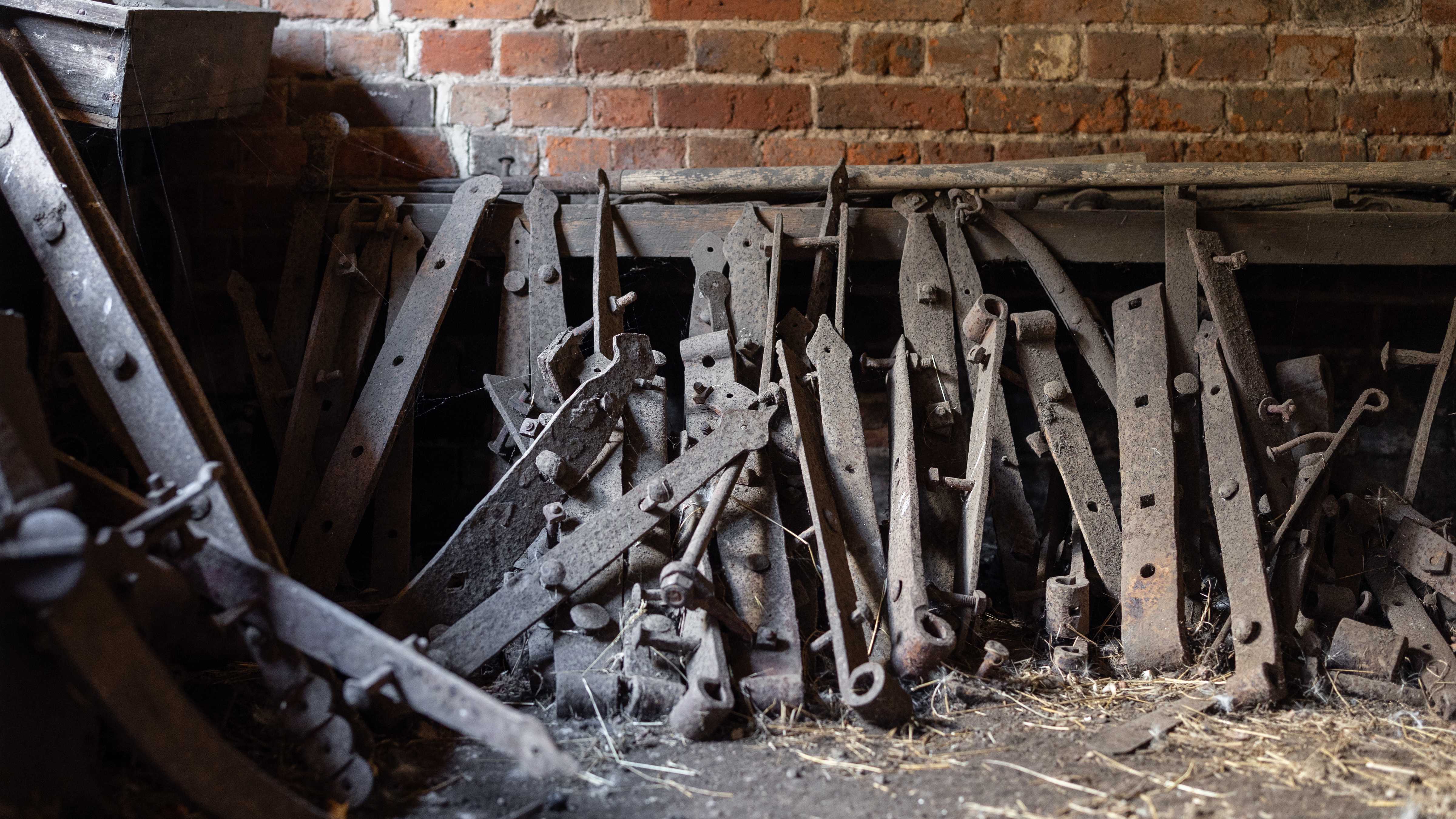 A collection of old metal gate hinges leaning on the brick wall of the Blacksmiths shop. Some of the hinges have metal bolts in them. Photo: Kate von Stieglitz / Tourism Australia.