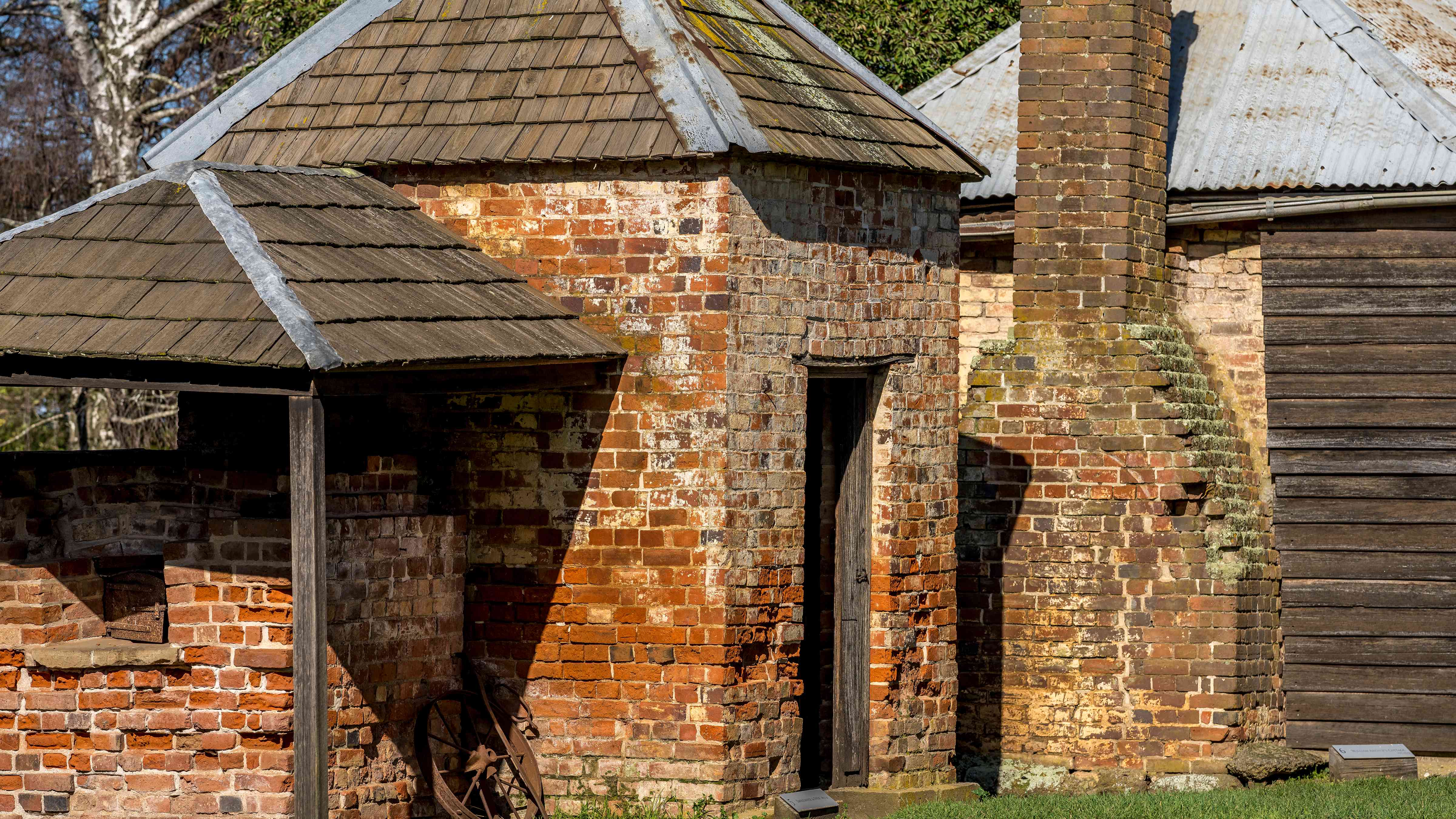 The bread oven and smoke house made from bricks that are multicoloured. The roofs are made from wooden shingles with iron and lead ridge caps . Next door is the side of a cottage with a brick chimney and corrugated iron roof. Photo: Rob Burnett.
